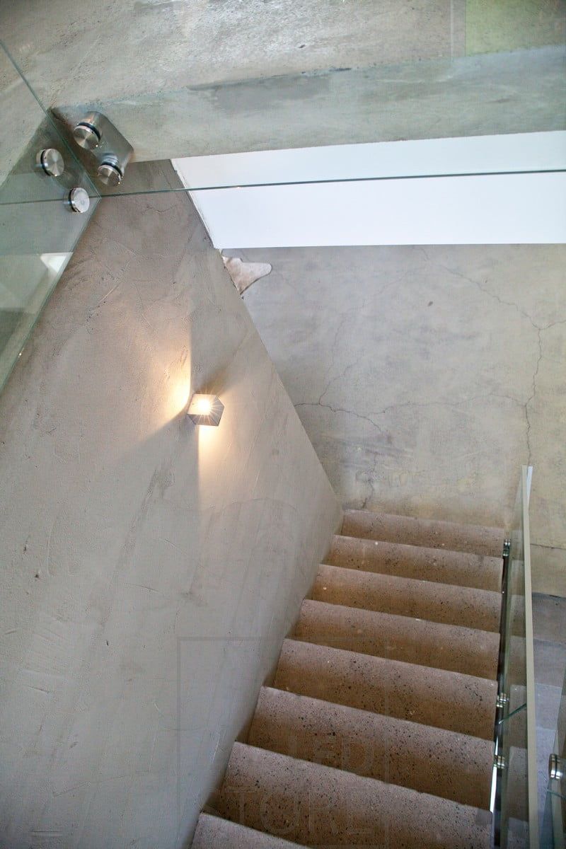 A bi-directional wall lamp illuminating the stairs.